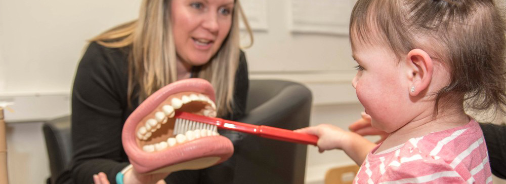 An image of a child being taught about dental hygiene.